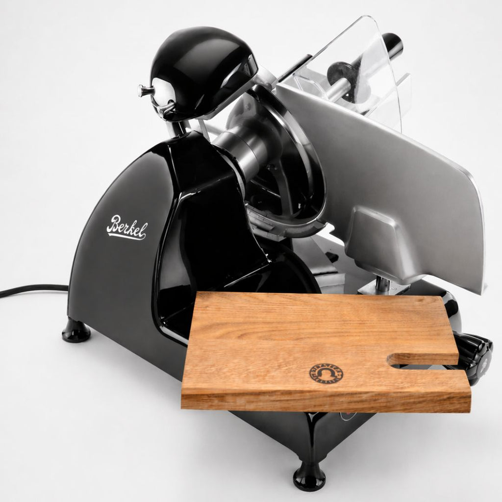 Ein Palatina-Werkstatt Einlegebrett für Berkel Red Line 250/300 Aufschnittmaschine steht vor einer glänzenden schwarzen Schneidemaschine im Vintage-Stil, die beide auf einer weißen Fläche ausgestellt sind.