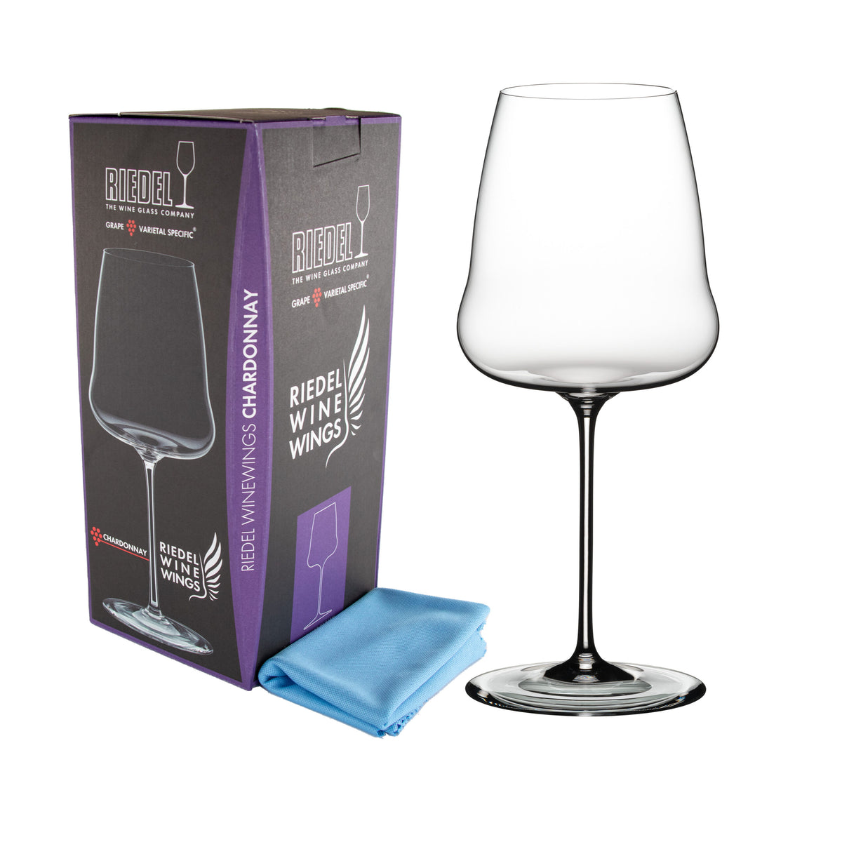 Ein Weißweinglas Riedel Winewings Chardonnay Glas mit Poliertuch in Geschenkverpackung steht neben seiner Verpackung und einem gefalteten blauen Tuch. Die Geschenkverpackung ist größtenteils schwarz mit violetten Akzenten und zeigt ein Bild des Weinglases. Der Text auf der Verpackung gibt die Marke und das Modell an, während das Glas ein schlankes, modernes Design aufweist.