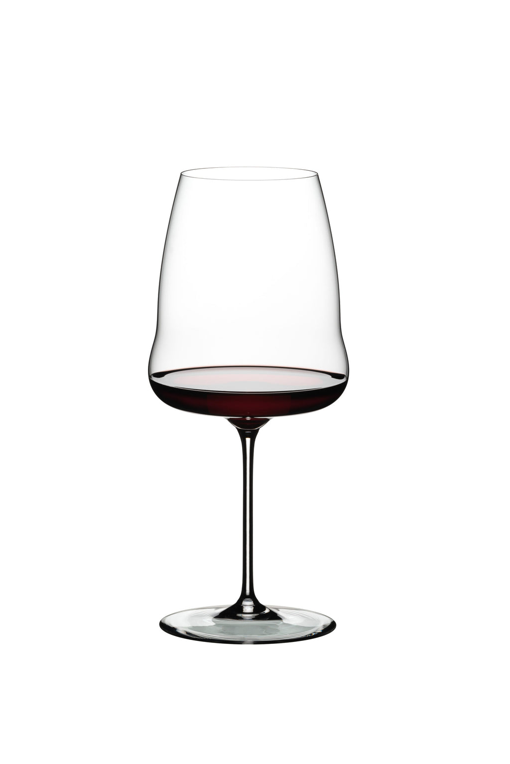 Ein klares Rotweinglas Riedel Winewings Syrah mit Poliertuch in Geschenkverpackung, gefüllt mit Rotwein, steht auf einem weißen Hintergrund. Das für Syrah entworfene Glas hat einen langen Stiel und eine leicht ausgestellte Schale, die die dunkelrote Flüssigkeit im Inneren zur Geltung bringt.