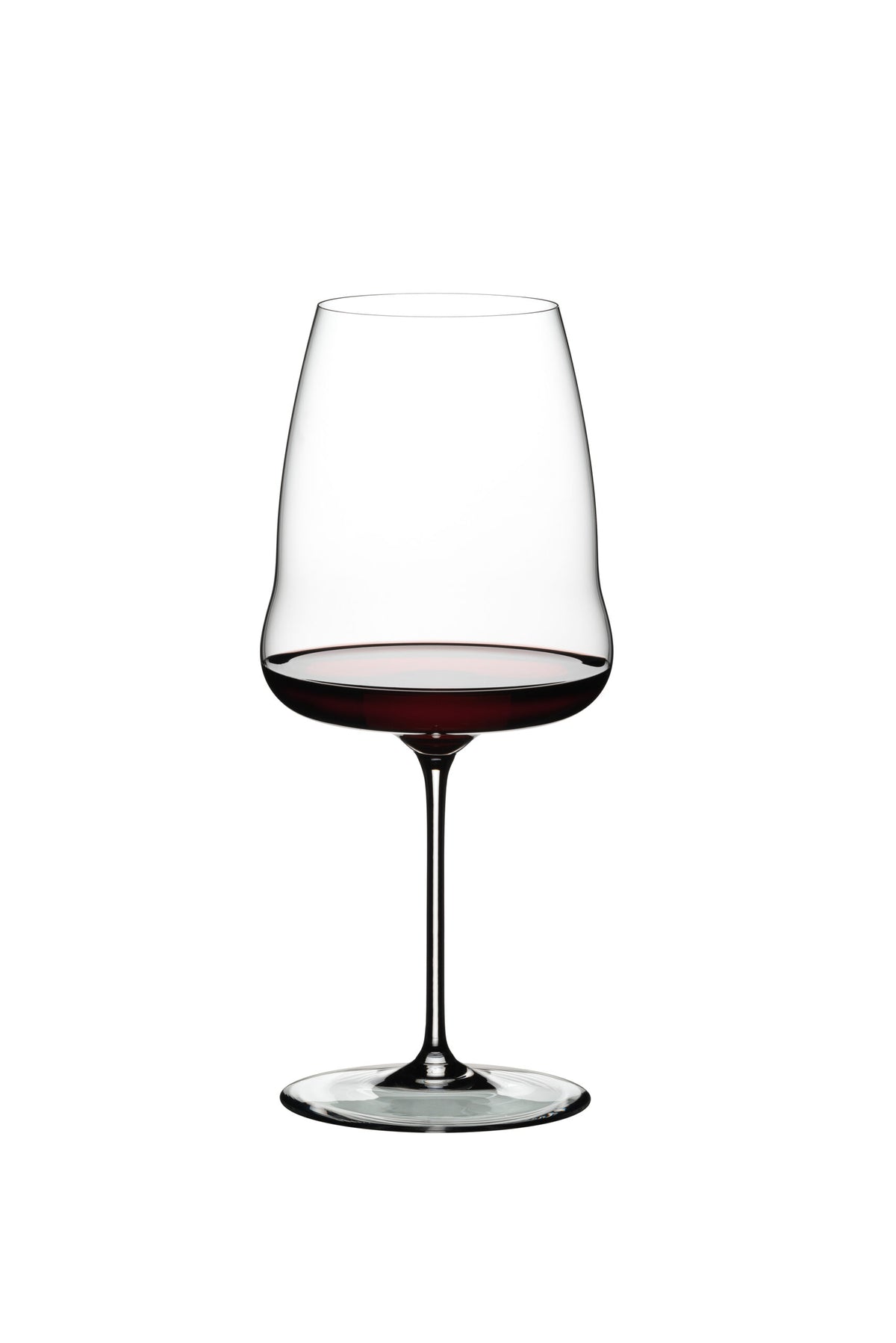 Ein klares Rotweinglas Riedel Winewings Syrah mit Poliertuch in Geschenkverpackung, gefüllt mit Rotwein, steht auf einem weißen Hintergrund. Das für Syrah entworfene Glas hat einen langen Stiel und eine leicht ausgestellte Schale, die die dunkelrote Flüssigkeit im Inneren zur Geltung bringt.
