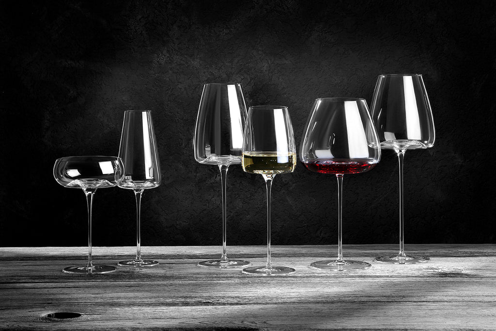 Sechs Zieher Weingläser Balanced Vision-Serie XXL 850 ml aus mundgeblasenem Kristall sind auf rustikalem Holz arrangiert, zwei davon gefüllt mit Weiß- und Rotwein. Ein dunkler Hintergrund unterstreicht ihre elegante Klarheit und die zarten Reflexe.