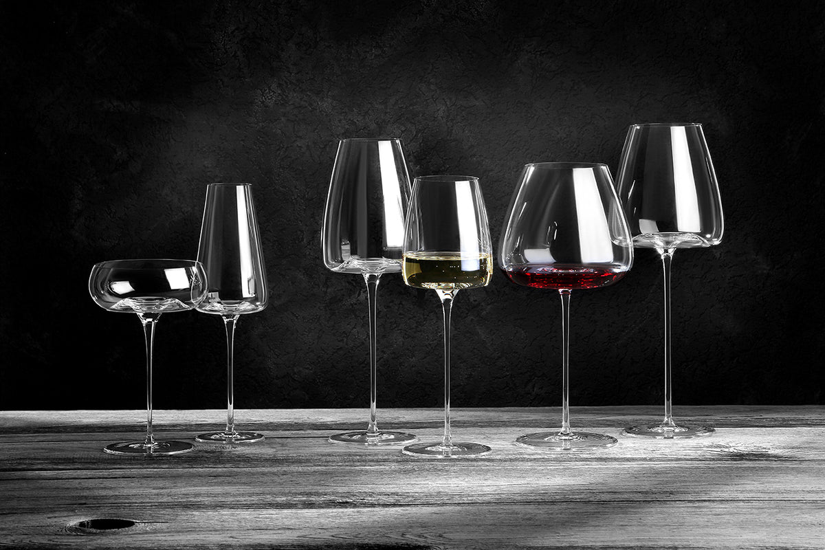 Sechs Zieher Weingläser Balanced Vision-Serie XXL 850 ml aus mundgeblasenem Kristall sind auf rustikalem Holz arrangiert, zwei davon gefüllt mit Weiß- und Rotwein. Ein dunkler Hintergrund unterstreicht ihre elegante Klarheit und die zarten Reflexe.