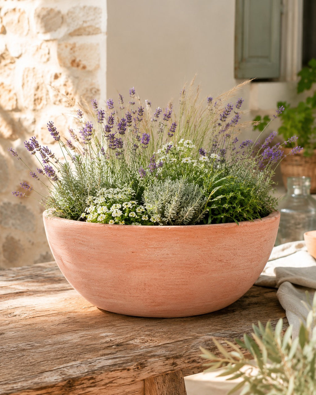 Die moderne Pflanzschale mit einem Durchmesser von 29–50 cm, gefüllt mit blühendem Lavendel, weißen Blumen und grünem Laub, steht auf einem rustikalen Holztisch in sonniger Umgebung.