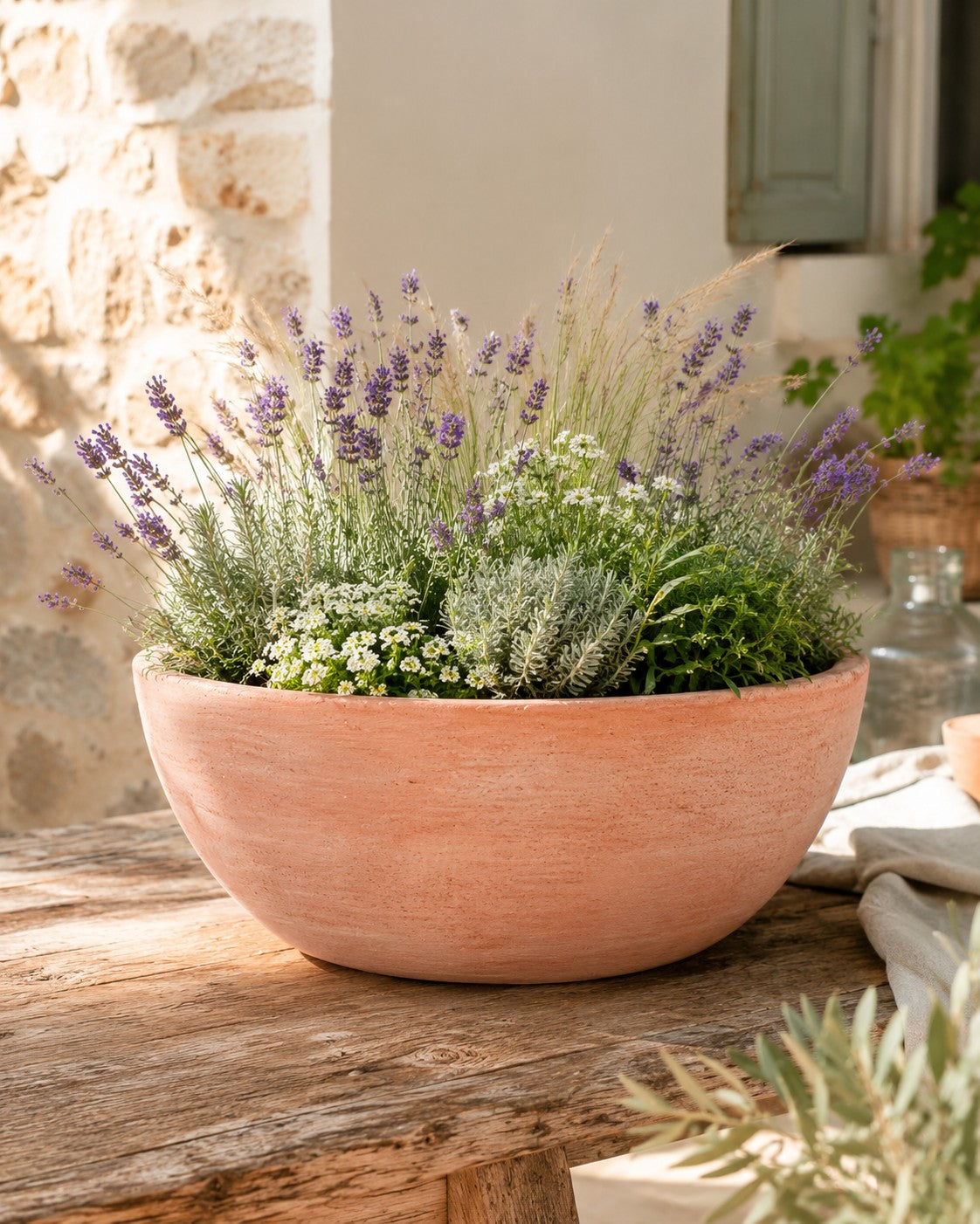 Die moderne Pflanzschale mit einem Durchmesser von 29–50 cm, gefüllt mit blühendem Lavendel, weißen Blumen und grünem Laub, steht auf einem rustikalen Holztisch in sonniger Umgebung.