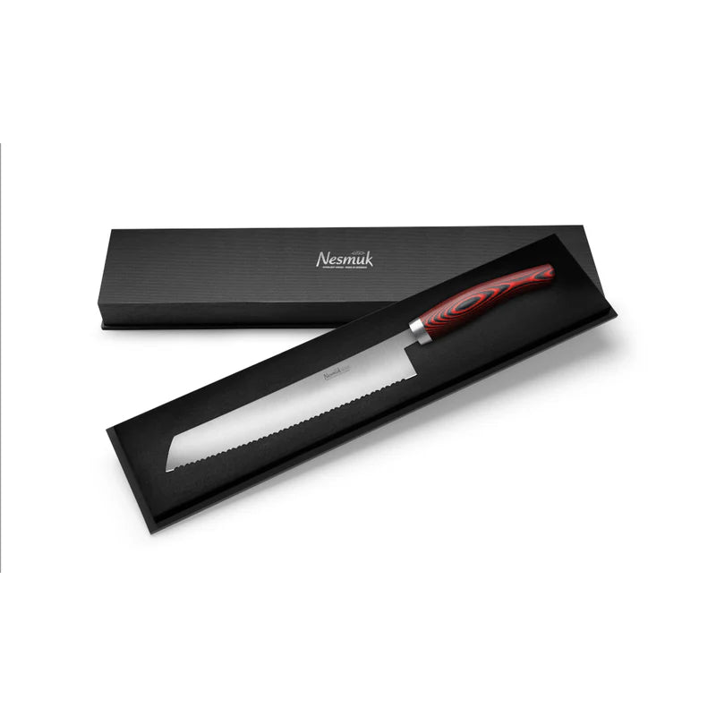 In einer offenen schwarzen Box wird ein Wellenschliffmesser mit einer schlanken 270 mm langen Klinge und einem rot-schwarz gemusterten Griff präsentiert. Auf dem Deckel der Box, neben dem Nesmuk Soul Brotmesser 270 mm, verschiedene Griffmaterialien, steht der Markenname „Nesmuk“. Dieses Messer besticht durch ein modernes und elegantes Design.