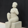 Die UV-beständige Gartenfigur "Badenixe" zeigt eine sitzende Frau im strukturierten Badeanzug und Badekappe, mit erhobenem Knie und Hand auf der Brust - eine stilvolle Gartendekoration vor schwarzem Hintergrund.