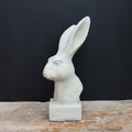 Die handgefertigte Steinfigur "Hase" aus Deutschland sitzt elegant auf einer Steinfläche.