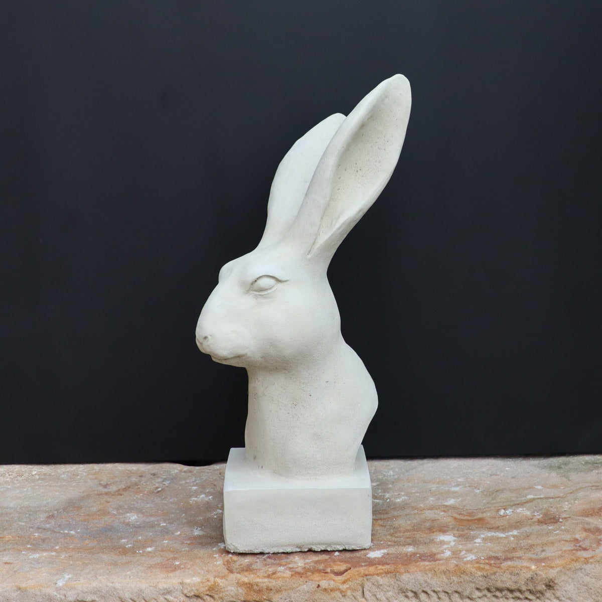 Die handgefertigte Steinfigur "Hase" aus Deutschland sitzt elegant auf einer Steinfläche.