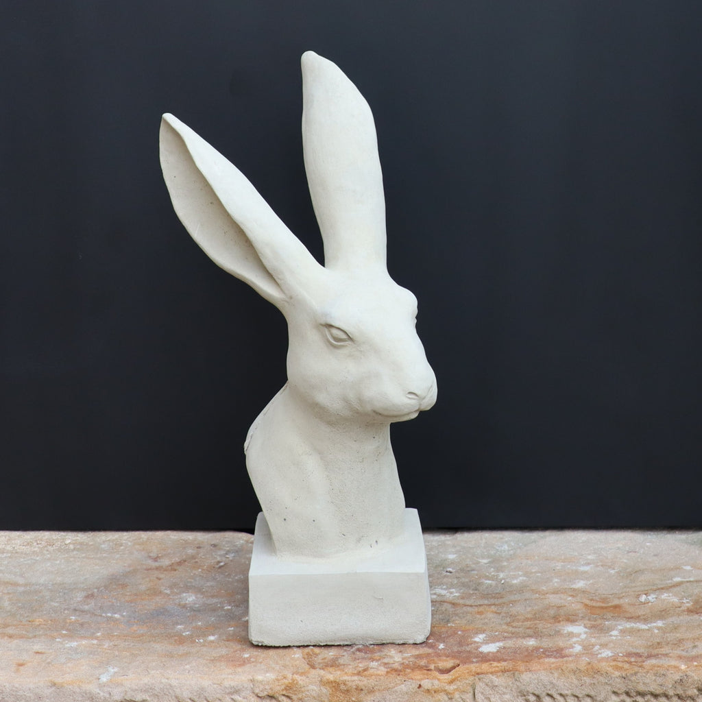 Die handgefertigte Steinfigur "Hase" aus Deutschland zeigt einen weißen Kaninchenkopf mit langen Ohren, präsentiert auf Stein vor schwarzem Hintergrund.