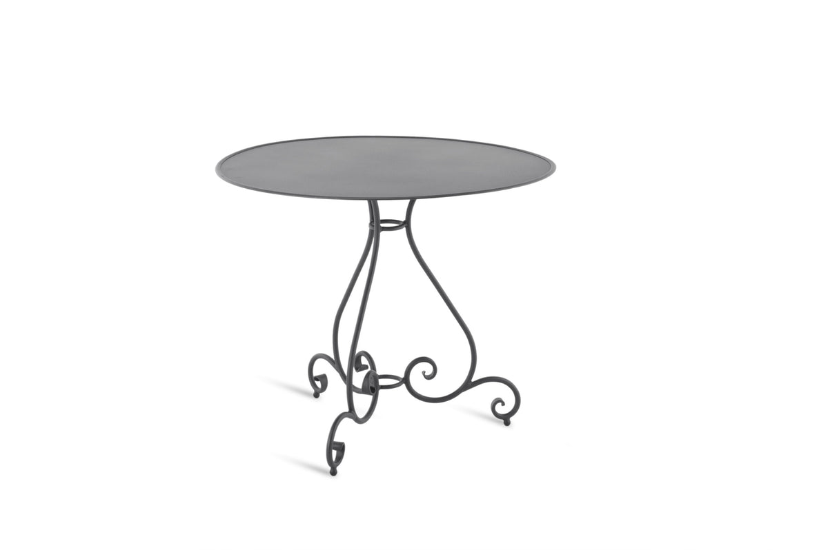 Ein kleiner, runder Metalltisch mit glatter, flacher Tischplatte, genannt „Tisch rund Aurora Ø cm 90“. Der Tisch verfügt über einen verzierten, geschwungenen Sockel aus Schmiedeeisen, der mit elegantem Schnörkelwerk verziert ist. Er ist schlicht und doch dekorativ und eignet sich sowohl für den Innen- als auch für den Außenbereich.