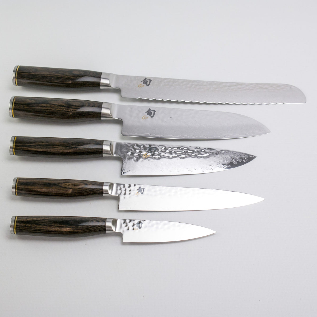 Das Exklusives Messerblock-Set - KAI Shun Tim Mälzer Damastmesser mit hochwertigem Magnet-Messerblock aus Walnuss von Böker besteht aus fünf Messern im japanischen Stil mit dunklen Holzgriffen und gehämmerten Klingen, ideal für die elegante Aufbewahrung.