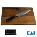Ein scharfes Kai Shun Premier Tim Mälzer Minamo TMM-0701 Allzweckmesser mit schwarzem Griff ruht auf einem hölzernen Schneidebrett aus altem Fassholz (Eiche) mit den Maßen 25x15 cm. Dem ultrascharfen Allzweckmesser mit 15 cm langer Klinge liegt ein schwarzes Heft mit der Aufschrift „KAI“ bei, außerdem ist in der unteren rechten Ecke des Bildes das KAI-Logo abgebildet.