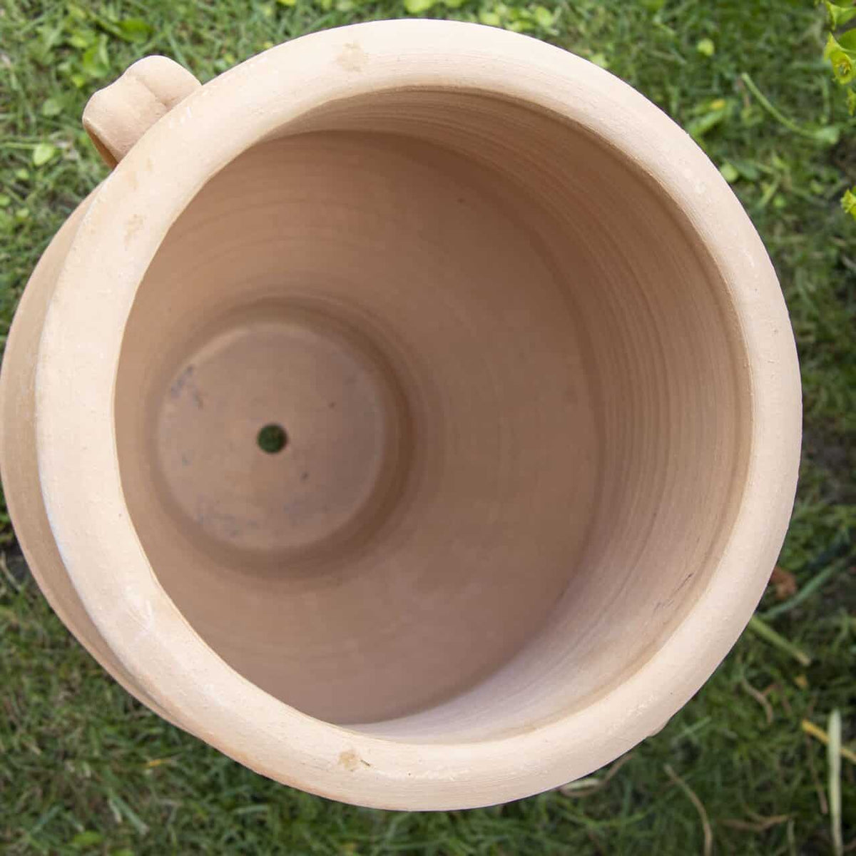 Draufsicht auf den leeren, runden Terrakotta-Blumentopf "Amphore zum Bepflanzen 'Thymus'" (H=40cm) mit Drainageloch, aufgestellt auf grünem Rasen - perfekt zum Bepflanzen und Dekorieren.