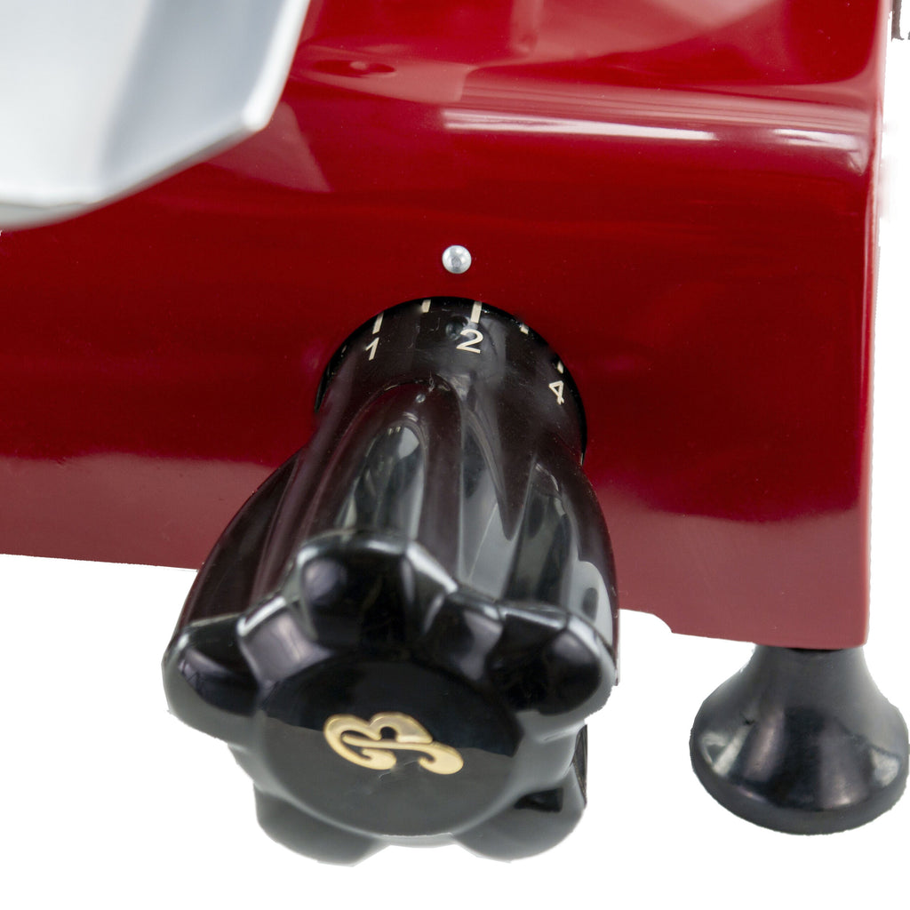 Nahaufnahme einer Berkel Red Line 300 Rot, Original Profi-Aufschnittmaschine mit rotem Gehäuse und verstellbarem schwarzen Drehknopf mit den Ziffern 0-2. Der glänzende Drehknopf, in dessen Mitte eine goldene Ziermarkierung angebracht ist, ist seitlich angebracht. Die Maschine steht auf schwarzen, saugnapfartigen Füßen und hat einen Messerdurchmesser von 300 mm.