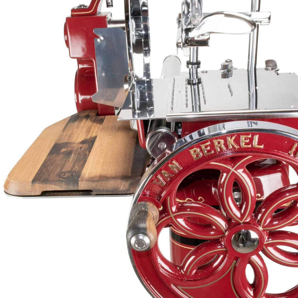 Eine Nahaufnahme zeigt die manuelle Aufschnittmaschine Berkel Volano B114 Rot mit passgenauem Einlegebrett, eine Vintage-Aufschnittmaschine für rotes Fleisch. Die Aufschnittmaschine verfügt über eine Handkurbel auf einem großen Rad, das mit komplizierten Mustern verziert ist, eine glänzende Schneide aus rostfreiem Stahl und ein tadellos passendes Schneidebrett. Sein Design strahlt eine kunstvolle, klassische Ästhetik aus.