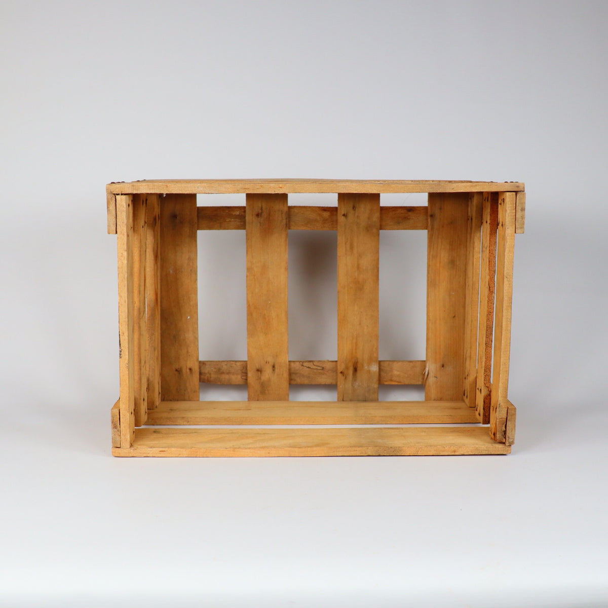 Eine Alte Weinkiste Holz Vintage aus der Pfalz mit Aufschrift, gekennzeichnet durch Lattenseiten und eine offene Oberseite, steht vor einem schlichten weißen Hintergrund. Die Kiste weist Gebrauchsspuren auf, mit sichtbarer Holzmaserung und kleinen Unvollkommenheiten, die ihren rustikalen Charme unterstreichen.