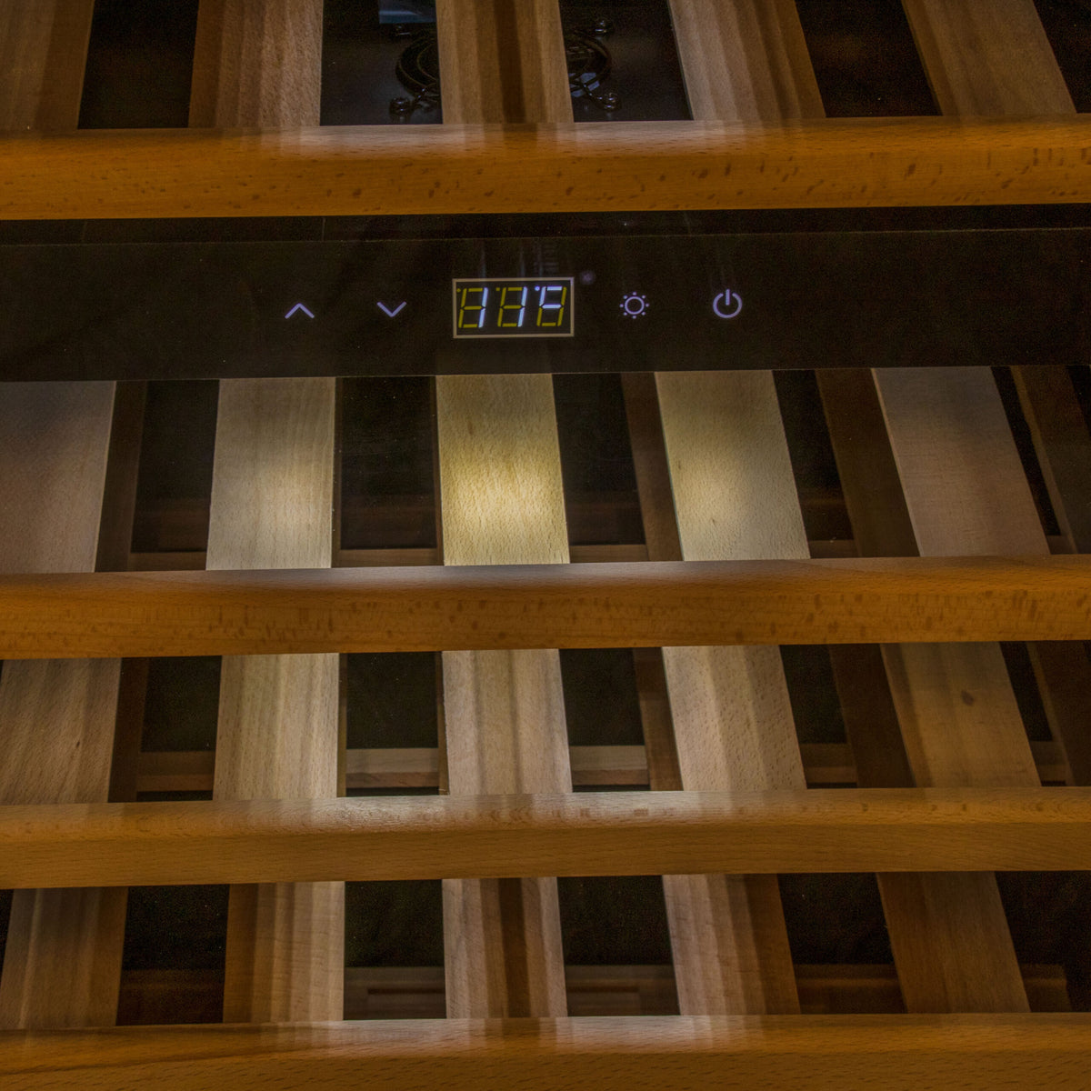 Nahaufnahme des Weinkühlschranks 2 Zonen CASO WineComfort 66 in Schwarz mit Fassholzumhausung. Holzregale sind sichtbar, die zur Lagerung von Weinflaschen verwendet werden. Das digitale Bedienfeld zeigt die Temperatur bei 13,6 °C an und verfügt über Tasten zum Anpassen der Einstellungen und zum Ein- und Ausschalten des Geräts. Der Kühler unterstützt zwei Zonen für eine optimierte Lagerung.