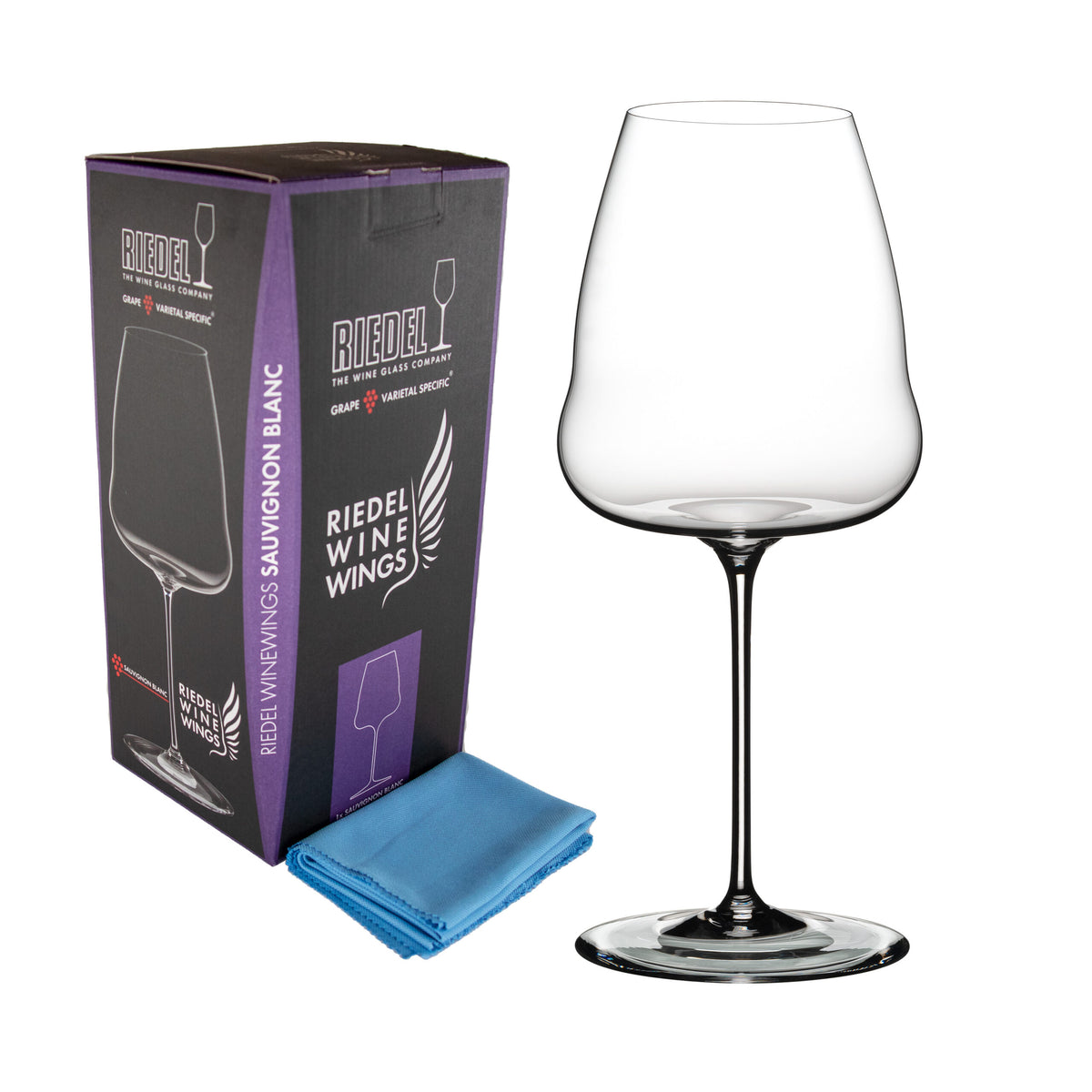 Ein klares Weißweinglas Riedel Winewings Sauvignon Blanc mit hohem Stiel steht neben einer violett-schwarzen Geschenkbox mit der Aufschrift „Riedel Winewings“. Vor der Box und dem Glas liegt ein gefaltetes blaues Poliertuch.
