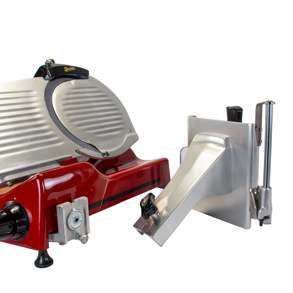 Ein rot-silberner Fleischschneider, genauer gesagt die Berkel Aufschnittmaschine Pro Line XS 25 Rot, Der Profi Allesschneider für Ihre Küche + 100% handgefertigtes Fassholzbrett Unikat, mit einem daneben platzierten abnehmbaren Teil. Der Profi Allesschneider verfügt über eine abgerundete Klingenabdeckung, einen Griff zur Bedienung und Einstellknöpfe. Das abnehmbare Teil scheint Teil des Fleischhalters oder des Schiebersystems zu sein.