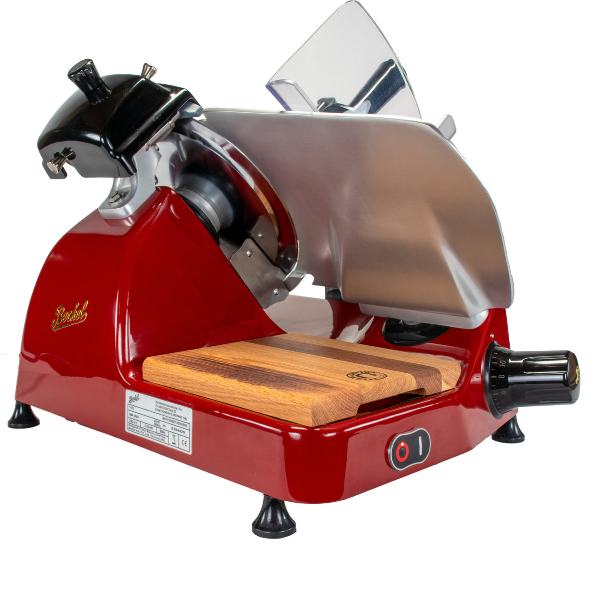 Eine Berkel Aufschnittmaschine Pro Line XS 25 Rot, der Profi Allesschneider für Ihre Küche, mit einer Klinge aus rostfreiem Stahl und einem 100 % handgefertigten Fassholzbrett Unikat darunter. Sie verfügt über einen schwarzen Griff, einen einstellbaren Dickenknopf und einen transparenten Sicherheitsschutz. Der Ein-/Ausschalter befindet sich bequem an der Vorderseite für einfachen Zugriff, was sie zur idealen Wahl für professionelles Schneiden macht.