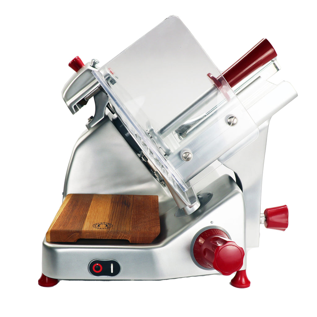 Bild einer professionellen Aufschnittmaschine Berkel Pro Line XS 25 Silber aus Edelstahl mit rotem Knopf und transparentem Klingenschutz. Sie verfügt über ein hölzernes Fassholz-Einlegebrett an der Basis, einen schwarzen Netzschalter mit roter Kontrollleuchte und zusätzliche rote Bedienknöpfe. Der Allesschneider ist auf einem schlichten weißen Hintergrund zu sehen.