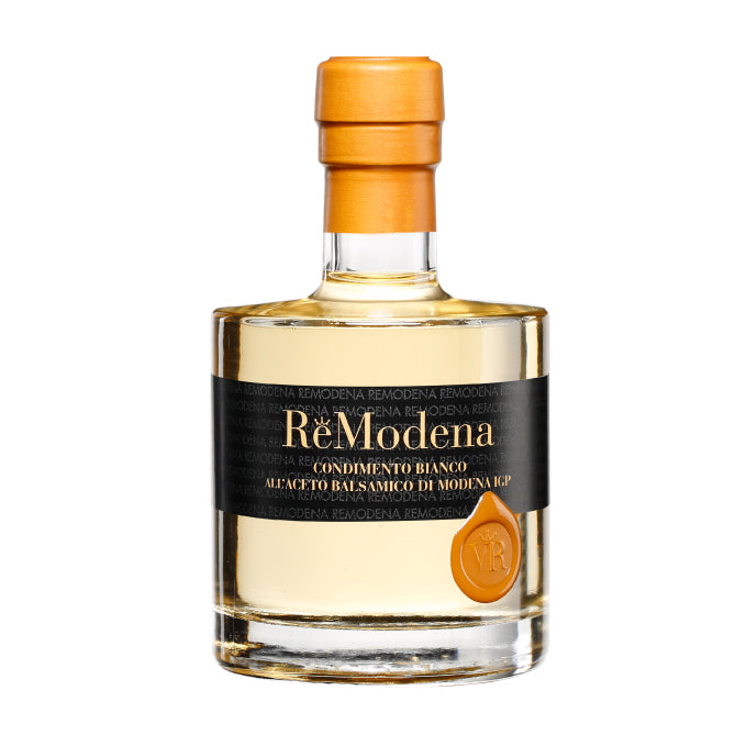 Eine Klarglasflasche mit dem Gewürz ReModena Bianco, die mit einem goldenen Wachssiegel und einem schwarzen Etikett mit goldener Schrift versehen ist. Die runde Flasche mit hellorangefarbenem Verschluss unterstreicht diesen exquisiten Balsamessig aus Modena.