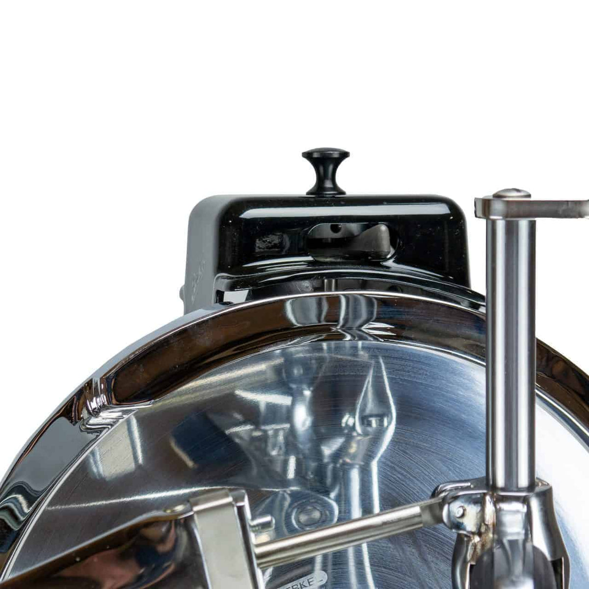 Eine Nahaufnahme eines glänzenden Küchengeräts aus Metall, möglicherweise ein Allesschneider. Das Bild zeigt das runde Schneideblatt, einen Griff und einen Teil des Bedienhebels. Die Oberfläche spiegelt die Umgebung wider und lässt vermuten, dass sie gut poliert und sauber ist.