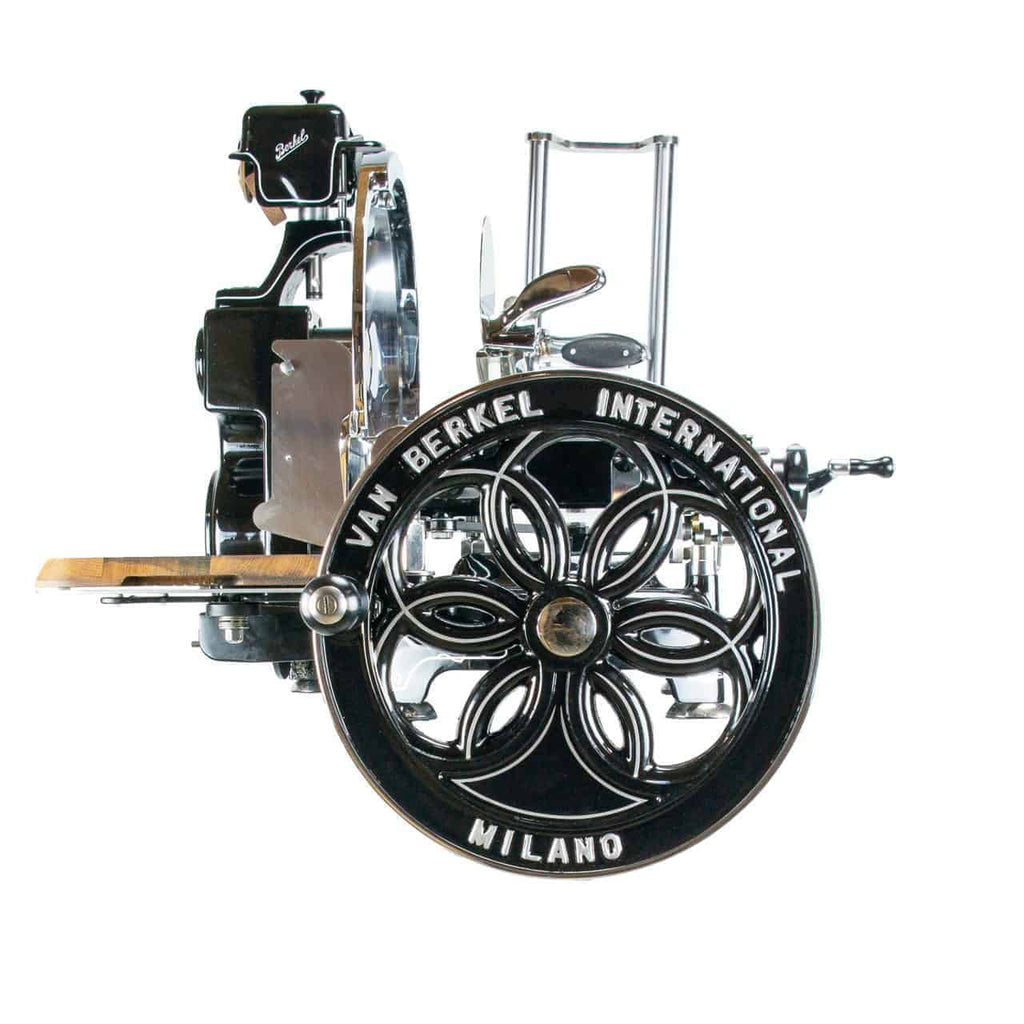 Ein klassischer Fleischschneider von Van Berkel International mit einem aufwendig gestalteten Schwungrad. Die Maschine hat eine schwarze und verchromte Oberfläche und zeichnet sich durch detaillierte Handwerkskunst aus. Der Name „Milano“ ist deutlich auf dem Schwungrad zu sehen.