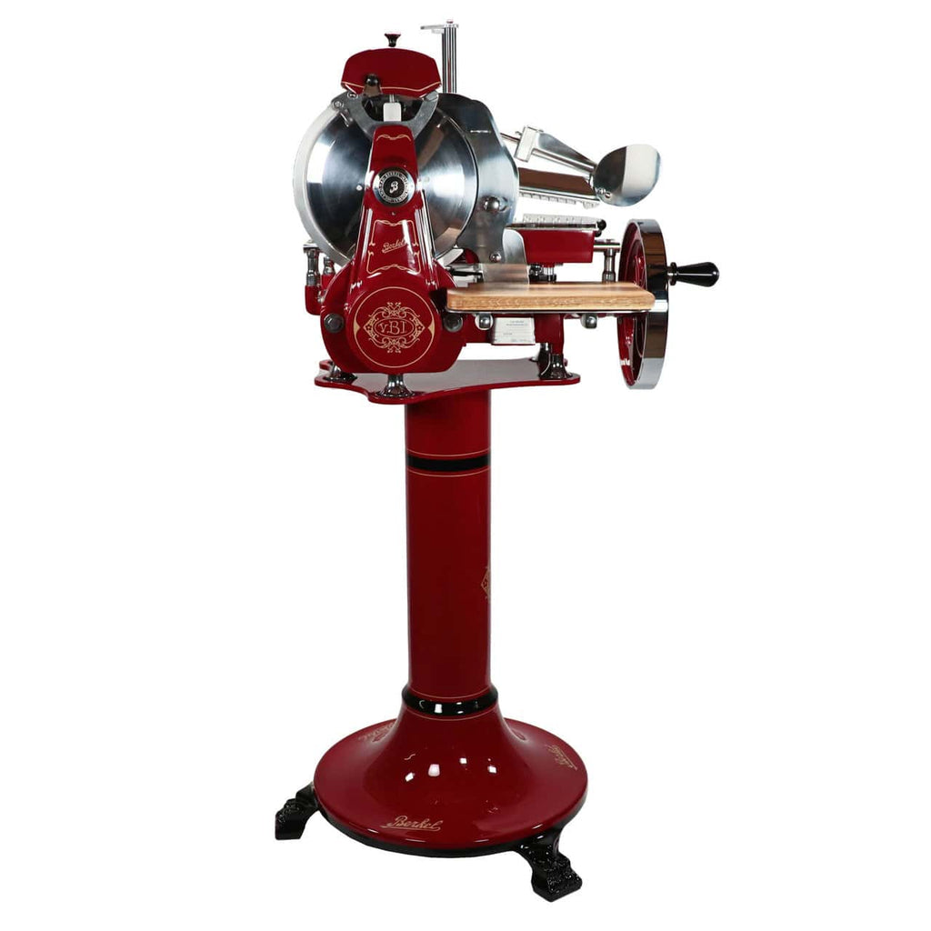 Die Berkel Volano B2 Schwungradmaschine in Rot ist eine atemberaubende Vintage-Fleischschneidemaschine mit Handkurbel, die auf einem hohen Sockel steht. Sie verfügt über ein großes rundes Messer, eine polierte Metalloberfläche und einen Holzarm zur Führung des Fleisches. Diese Aufschnittmaschine ist mit kunstvollen Details verziert und strahlt den klassischen, altmodischen Stil der Berkel Volano B2 aus. Sie wird mit einem einzigartigen Fassholzbrett geliefert.