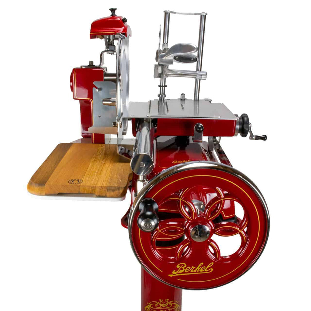 Eine rote Berkel Volano B3 Rot, Schwungrad-Aufschnittmaschine im Vintage-Stil mit glänzendem Metallrad und aufwendig gestalteter Handkurbel, einem links angebrachten Einlegebrett aus Fassholz und dem in Gold eingravierten Markennamen „Berkel“ auf der unteren Vorderseite vor weißem Hintergrund.