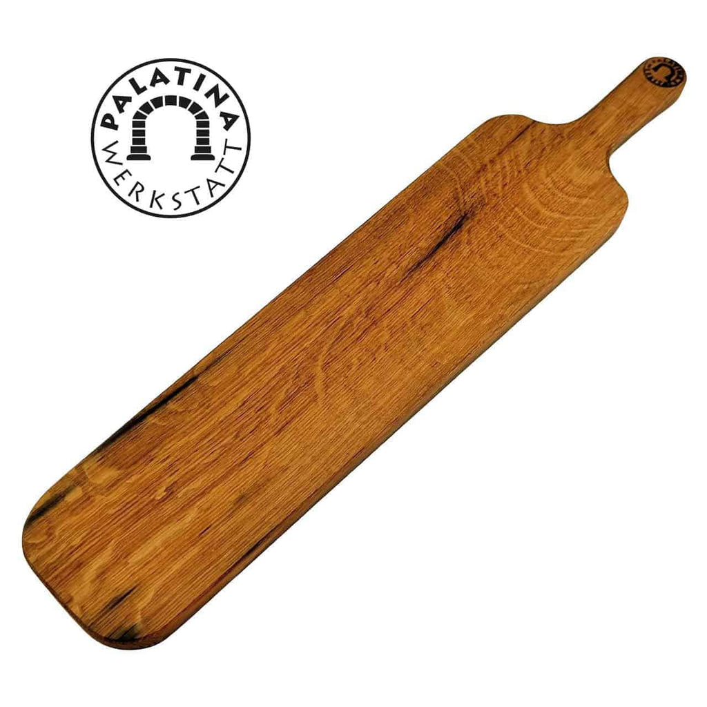 Ein langes, rechteckiges Baguettebrett aus Holz von Palatina Werkstatt, gefertigt aus Weinfassholz mit einem kleinen Griff an einem Ende. Das Brett weist eine natürliche Holzmaserung auf und trägt das Logo von Palatina Werkstatt mit einem Bogendesign in der Ecke.
