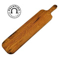 Ein langes, rechteckiges Baguettebrett aus Holz von Palatina Werkstatt, gefertigt aus Weinfassholz mit einem kleinen Griff an einem Ende. Das Brett weist eine natürliche Holzmaserung auf und trägt das Logo von Palatina Werkstatt mit einem Bogendesign in der Ecke.