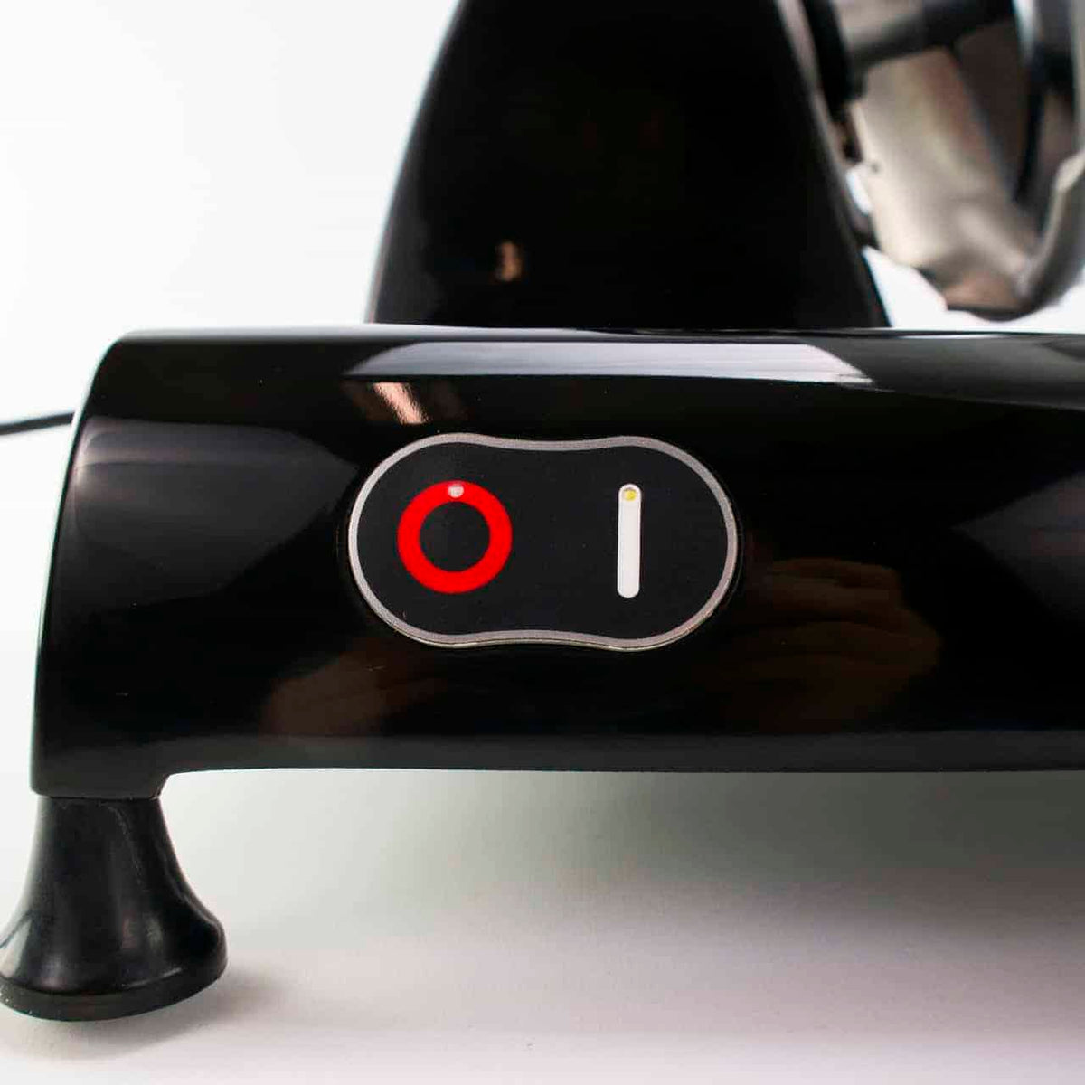 Nahaufnahme des Netzschalters eines schwarzen Elektrogeräts. Der Schalter befindet sich in der Position „Ein“, wobei ein roter Kreis und eine weiße vertikale Linie den Stromstatus anzeigen. Das Gerät scheint eine schwarze, glänzende Oberfläche zu haben und steht auf einer weißen Oberfläche.