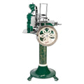 Das Berkel Volano B114 Sondermodell Schwungradmaschine incl. Standfuß + Fassholzbrett hat ein grün-silbernes Vintage-Design, ein verziertes Rad mit Blumenmuster, Emaille- und Metallakzente und steht auf einem passenden dekorativen Sockel.