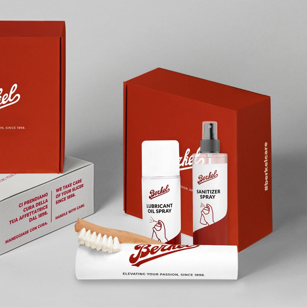 Bild eines Produktsets mit der Bezeichnung „Berkel“, bestehend aus einem Schmierölspray, einem Desinfektionsspray, einer Holzbürste und rot-weißen Verpackungsschachteln. Der Text auf der Verpackung betont die Tradition der Marke und die Sorgfalt, die sie für hochwertige Schneidegeräte legt. Es ist das perfekte Reinigungs- und Instandhaltungsset für Ihre Küchenbedürfnisse.