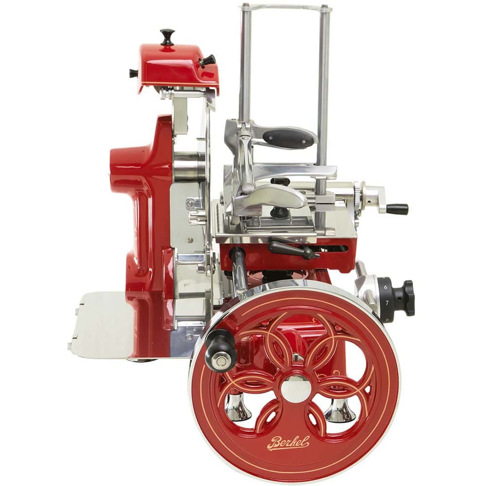 Eine Berkel Volano B2 Rot Schwungradmaschine im Vintage-Stil mit großem Handrad, Chromakzenten und montiertem Messerschärfer. Das aufwendige Design und die polierte Oberfläche verleihen dieser Aufschnittmaschine ein klassisches Retro-Aussehen. Dieser schöne Fleischschneider verfügt außerdem über ein exquisites, für dieses Modell einzigartiges Fassholzbrett, das ihn perfekt zum präzisen Schneiden von Fleisch und Käse macht.