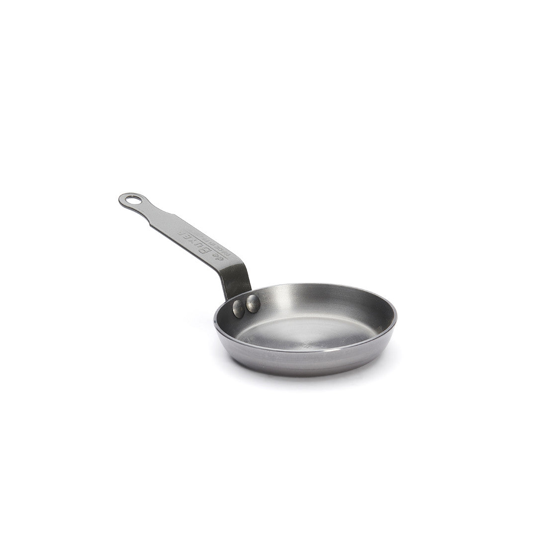 Die De Buyer Blinis-Pfanne Mineral B ist eine kleine, runde Pfanne aus rostfreiem Stahl mit einem flachen Boden und einem langen Stiel mit einem Loch am Ende, abgebildet auf einem schlichten weißen Hintergrund.