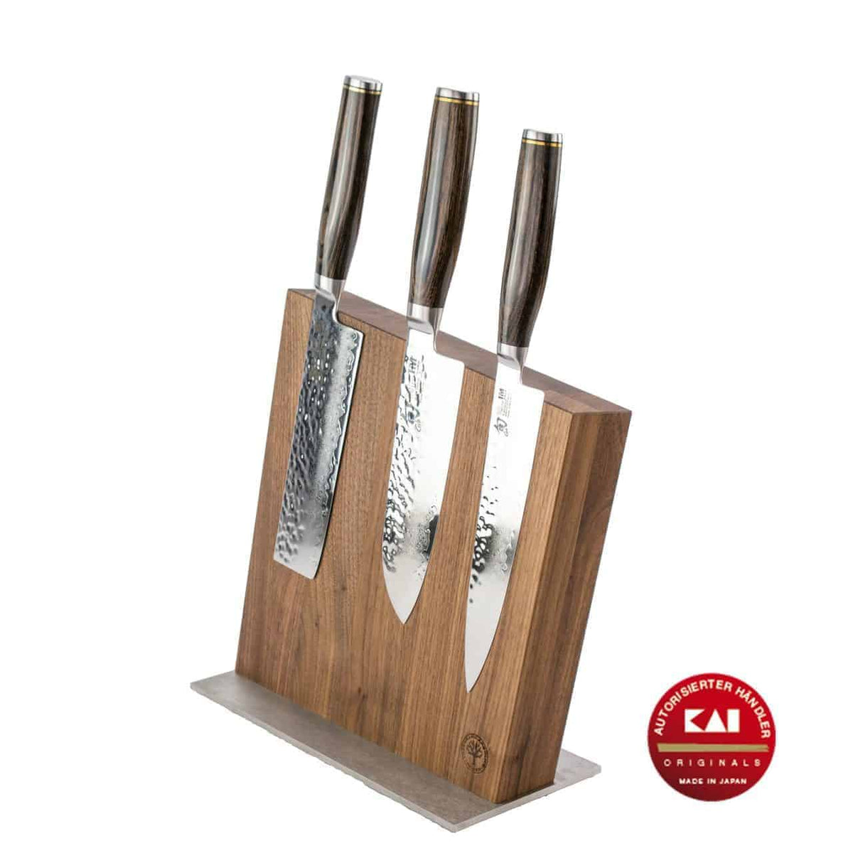 Ein Set aus drei hochwertigen KAI Shun Tim Mälzer Damastmessern mit Holzgriffen wird in einem eleganten Messerblock aus Holz präsentiert. Die Messer haben gehämmerte, reflektierende Klingen. Rechts befindet sich ein rundes rotes Emblem mit weißem Text, auf dem „KAI“ und „Made in Japan“ steht.