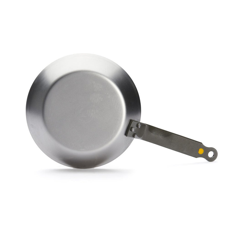 Die De Buyer Bratpfanne Mineral B aus Edelstahl wird von oben gezeigt - sie hat einen flachen Boden, einen langen Metallgriff mit gelbem Akzent am Ende und eignet sich ideal zum scharfen Anbraten.