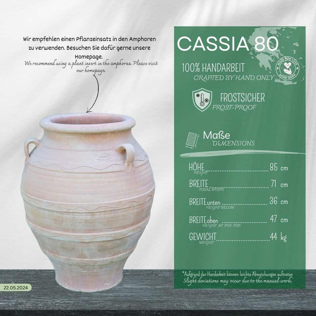 Eine beigefarbene Keramikamphore steht auf einer Holzfläche. Daneben steht in einer grünen Schachtel die winterfeste Dekorationsamphore "Cassia", H=70 cm, die in deutscher und englischer Sprache auf ihre frostsicheren, handgefertigten Eigenschaften hinweist.