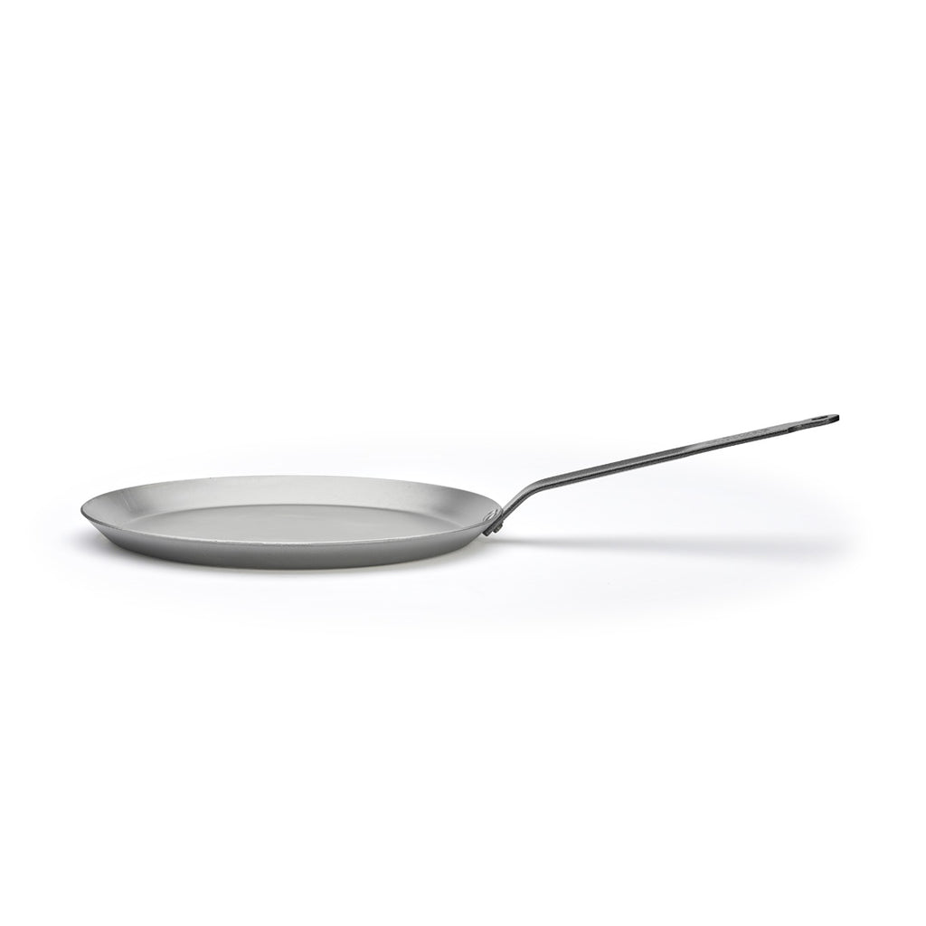 Eine flache, runde, silberne De Buyer Crêpe-Pfanne Carbone Plus mit langem Griff, von der Seite gesehen auf weißem Hintergrund.