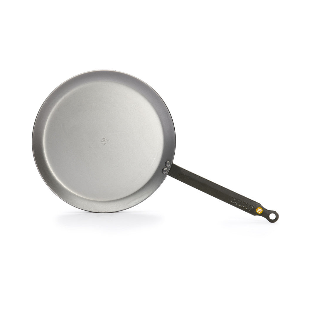 Die De Buyer Crêpe-Pfanne Mineral B (26 cm) ist eine runde, silberne Pfanne mit langem, geradem, schwarzem Stiel, abgebildet auf weißem Hintergrund.