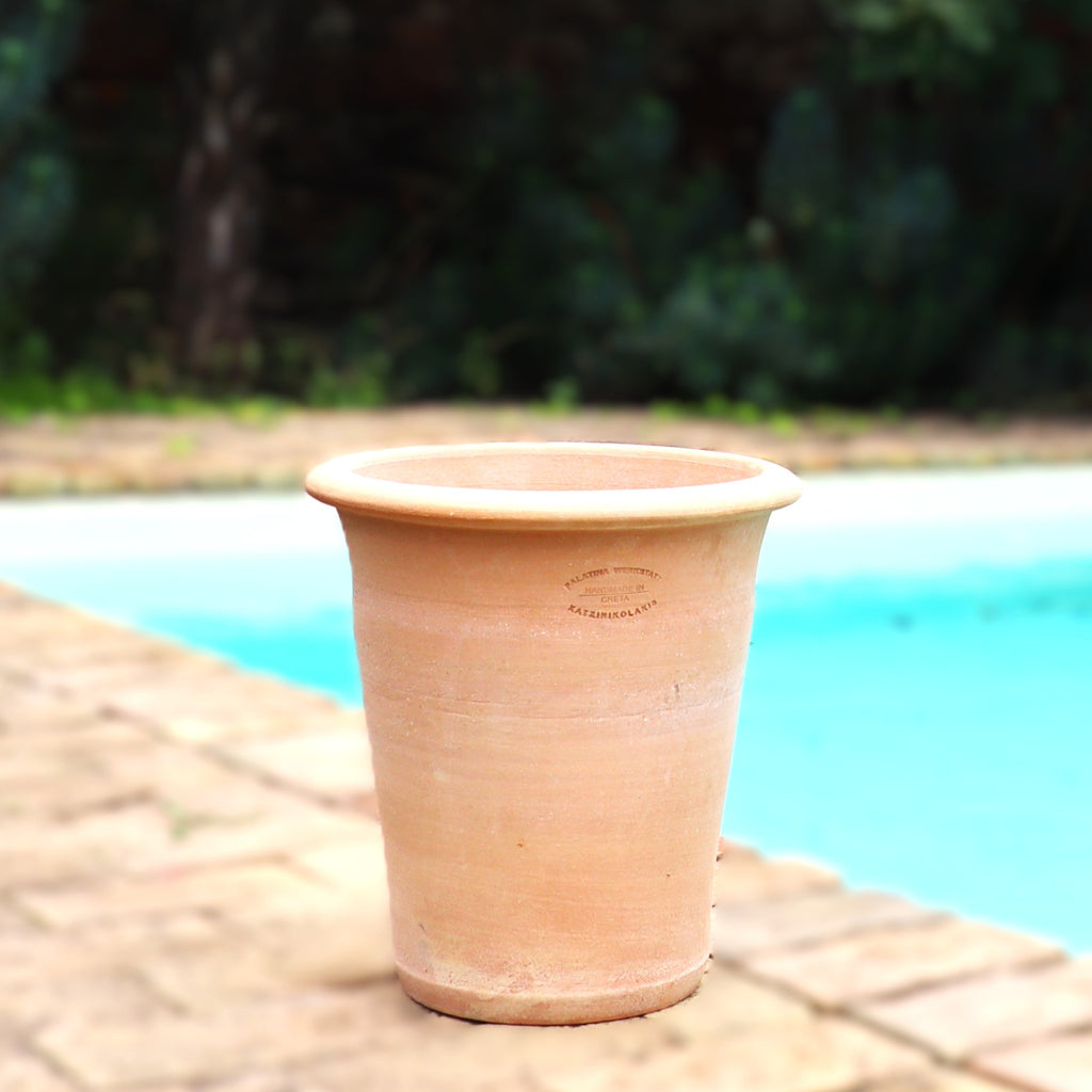 Ein leerer Terrakotta Pflanztopf "Dahlia" 35 cm - handgemacht & frostfest - steht auf einer Steinterrasse neben einem Pool, im Hintergrund verschwimmt grünes Laub.