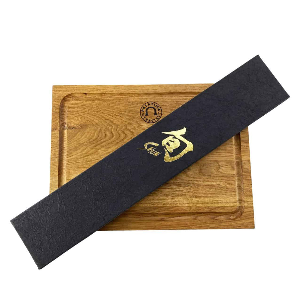 Eine schwarze, rechteckige Box, verziert mit goldenen japanischen Kanji-Zeichen und einer diagonal platzierten Signatur auf einem hölzernen Schneidebrett mit Rillen und einem eingravierten Logo in der oberen Mitte, bringt die Eleganz des Kai Shun Classic DM-0704 Schinkenmessers mit seiner 23 cm langen Damaszenerklinge perfekt zur Geltung, begleitet von einem 30 x 22 cm großen Eichenbrett.