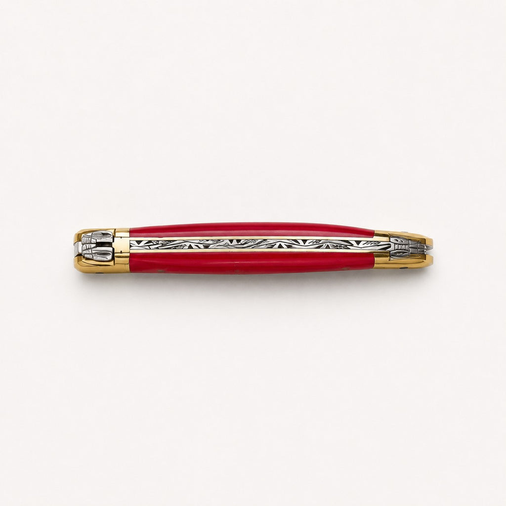 Ein geschlossenes rot-goldenes Taschenmesser mit silbernen Zierelementen entlang des Rückens, horizontal auf einem schlichten weißen Hintergrund dargestellt.