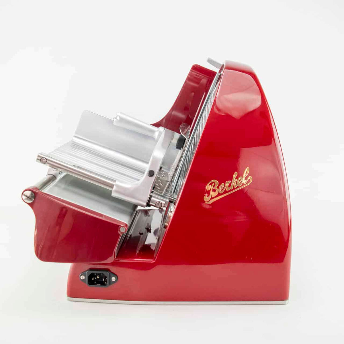 Eine Seitenansicht einer roten Berkel Home Line 250 Rot, Aufschnittmaschine + von Hand gefertigtes Fassholzbrett aus alten Weinfässern. Der Allesschneider hat ein schlankes, geschwungenes Design mit Chromakzenten und einem manuellen Griff. Der Markenname „Berkel“ ist in Gold auf der Seite geschrieben. Der Allesschneider steht vor einem schlichten weißen Hintergrund.