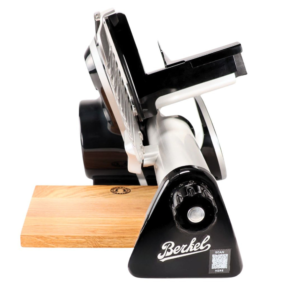 A Berkel Icon Line 170 in schwarz steht auf weißem Hintergrund, daneben ein handgefertigtes Einlegebrett aus Eiche (30x20 cm). Der Markenname "Berkel" ist auf der Vorderseite sichtbar.