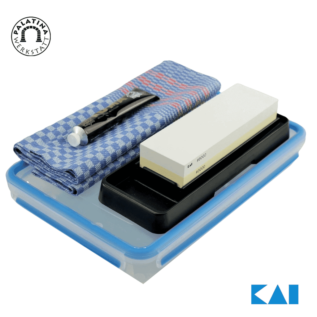 Das Kai 4-teilige Schleifstein- und Pflegeset AP-0316 wird gezeigt und besteht aus einem Schleifstein, einem blau-weiß karierten Tuch und einem kleinen Metallwerkzeug, alles in einem Kunststoffkoffer. Die Logos von Palatina Werkstatt und Kai sind jeweils in der oberen linken und unteren rechten Ecke zu sehen.