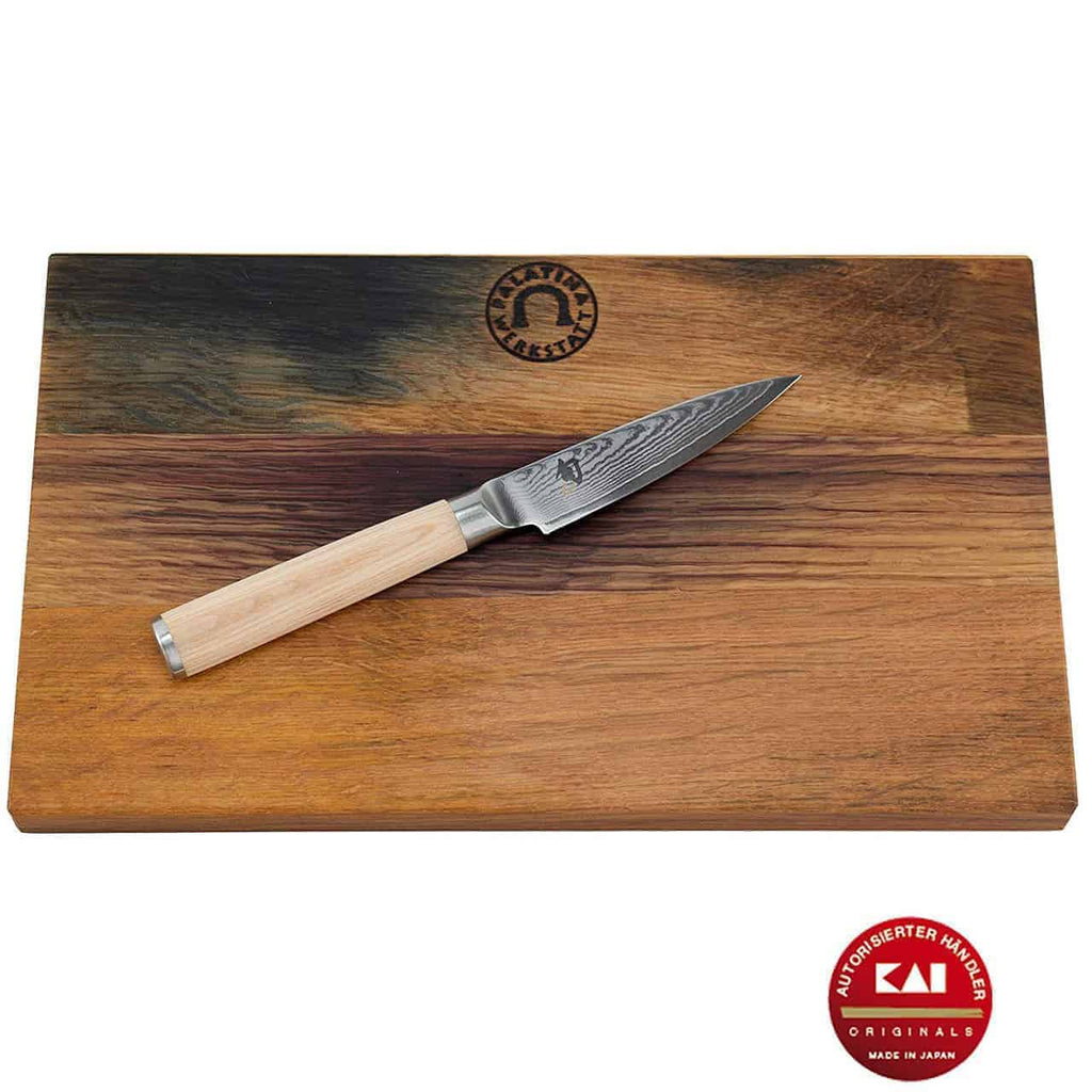 Das Kai Shun Classic White DM-0700W Officemesser mit 9 cm langer Damaszenerstahlklinge und hellem Holzgriff sitzt auf einem rechteckigen Schneidebrett aus Weinfassholz mit den Maßen 30x18 cm. Das Schneidebrett trägt oben in der Mitte ein Logo und das Bild wird durch das rote Kai Originals-Logo in der unteren rechten Ecke hervorgehoben, was die Kai Shun Classic-Qualität unterstreicht.