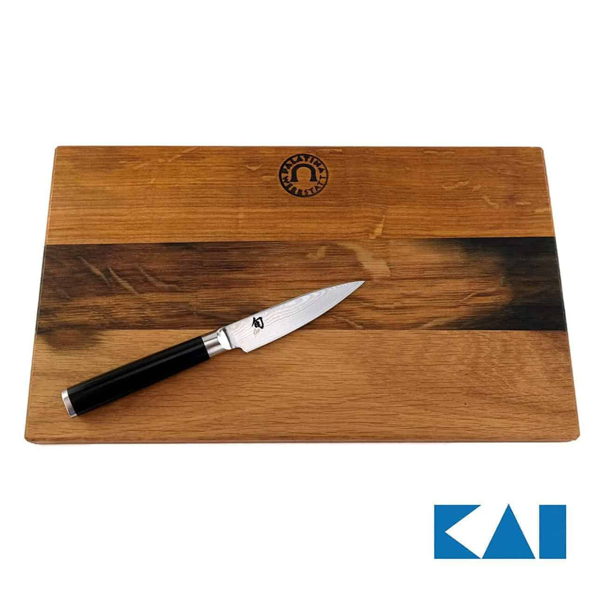 Auf einem 30x18 cm großen Holzschneidebrett aus Weinfassholz liegt schräg ein kleines Kai Shun Classic DM-0700 Officemesser (9 cm). Das Messer hat eine glänzende Klinge aus Damaszenerstahl und einen schwarzen Griff. In der Ecke ist ein Logo mit dem Text „KAI“ angebracht.